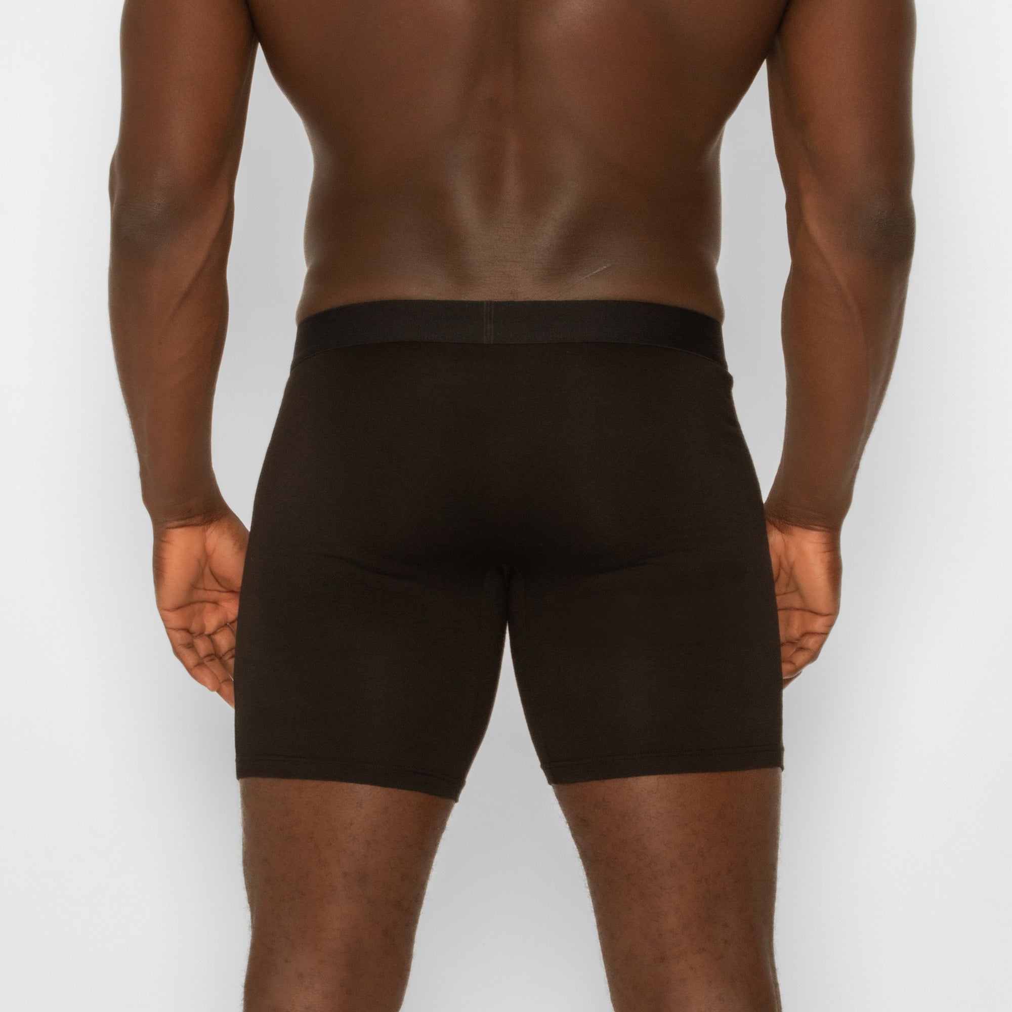Person wearing spicy wear black boxer briefs on a plain background